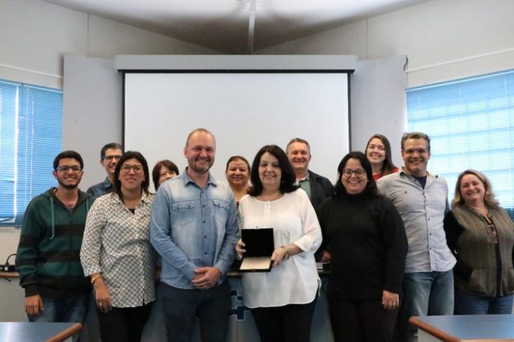 professora Osnara posa para foto com homenagem ao lado da equipe da UEPG