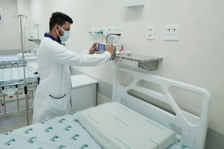 Enferemeiro ajustando aparelho em hospital.
